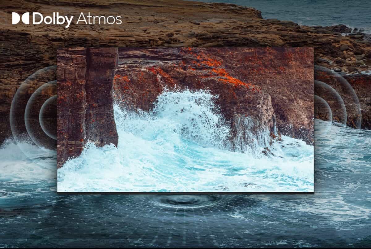 טלוויזיית Dolby Atmos: חווית קולנוע ביתי עוצמתית ומרתקת בתמונה זו רואים נוף מרהיב של גלים מתנפצים על חוף סלע. הטלוויזיה מוצגת על סטנד בסלון, וניתן לראות את לוגו Dolby Atmos על המסך. הטלוויזיה הזו מציעה חווית קולנוע ביתי עוצמתית ומרתקת הודות לטכנולוגיית Dolby Atmos. מערכת זו יוצרת תחושה תלת-ממדית של צליל